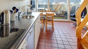 A kitchen with a stove, sink, and dining area with chairs.