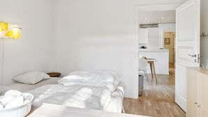 Un dormitorio moderno con techo de madera, una mesita de noche, una lámpara y vistas hacia una zona de cocina.