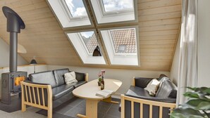 A cozy room with a modern loft design, featuring a sofa, a small table, and a built-in wood stove.