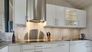 Eine moderne Küche mit weißen Schränken, Edelstahlgeräten und einer Holzbalkendecke.