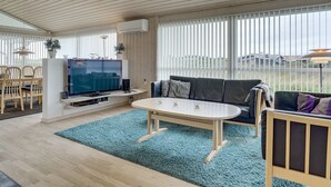 Ein modernes Wohnzimmer mit Fernseher, Sofa und Essbereich.
