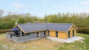 A modern two-story building with a sloped roof, large windows, and a covered outdoor area with a table and chairs. - "Arona" - 1.5km from the sea by Interhome (Fanø)