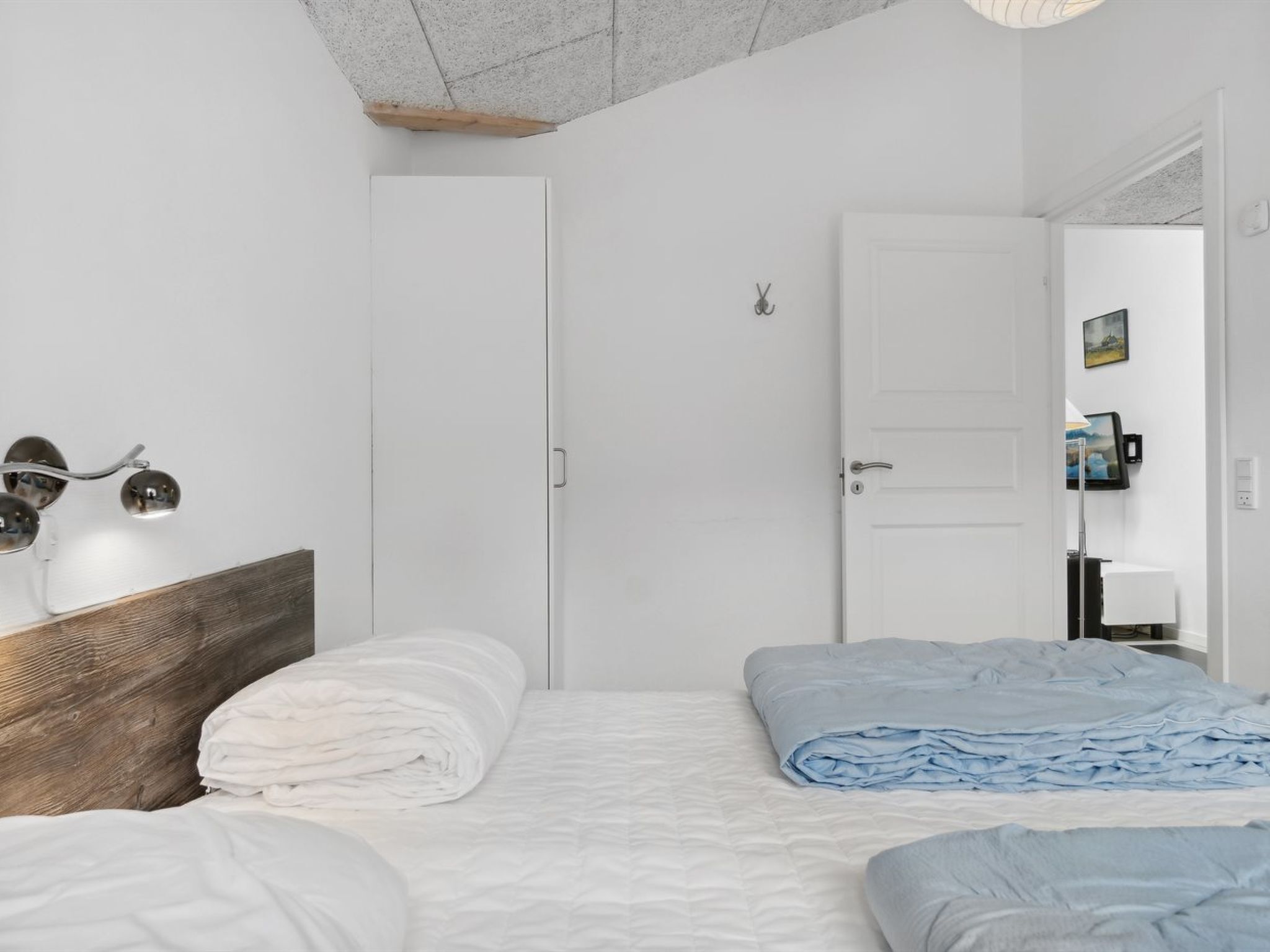Een slaapkamer met twee bedden, een houten hoofdbord, een witte deur en een klein raam.