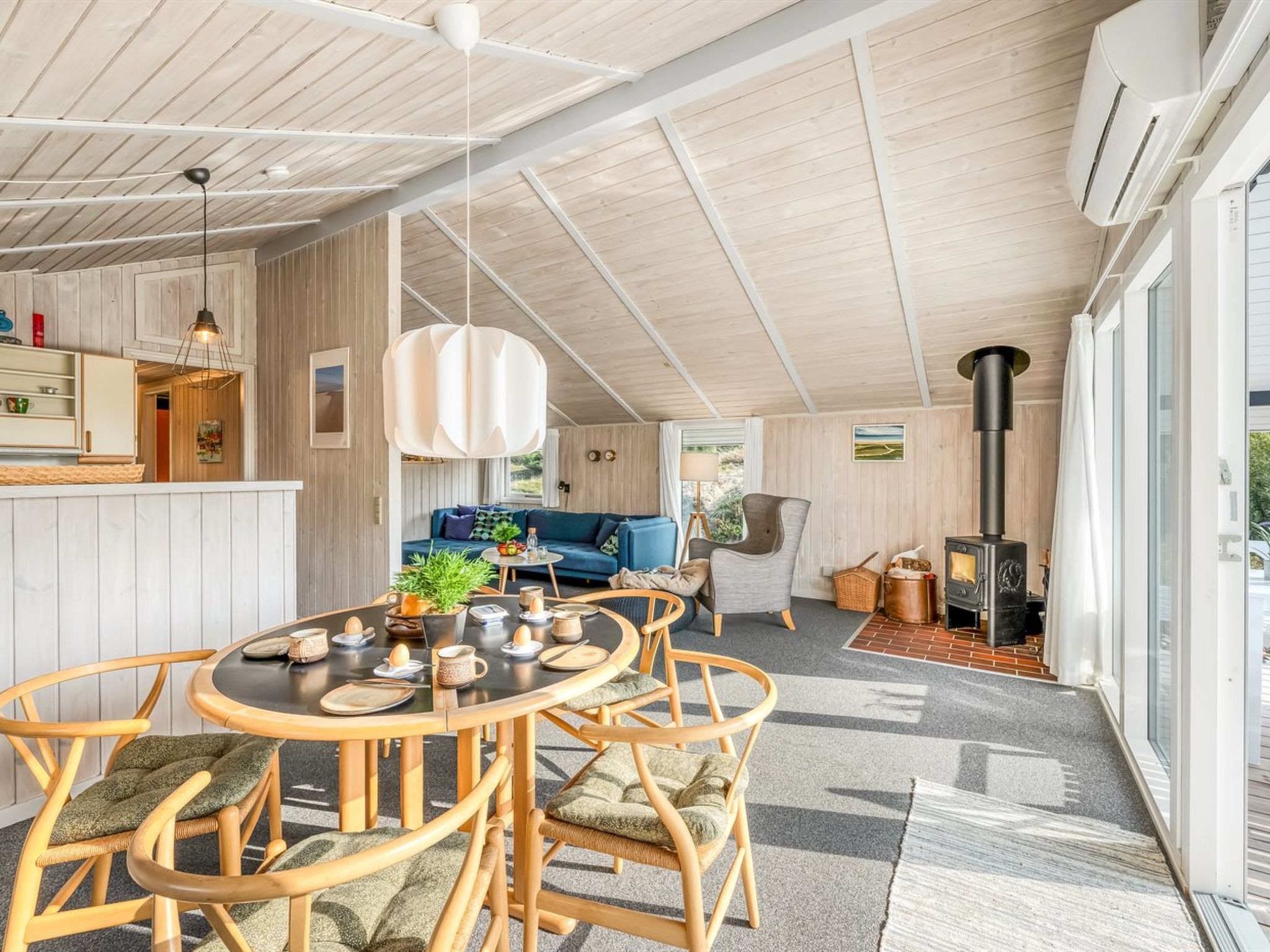A cozy, well-lit room with a round wooden dining table, comfortable seating, a sofa, and a fireplace.