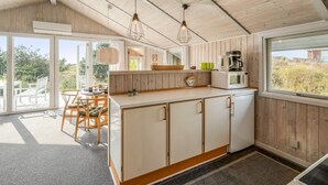 Una cocina moderna con armarios de madera, encimera blanca y un ventanal grande.
