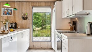 A modern kitchen with wooden walls, a large window, and a view of greenery outside.