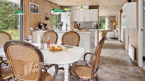 A modern kitchen with wooden cabinets, a dining area with wicker chairs, and a view of the outdoors.