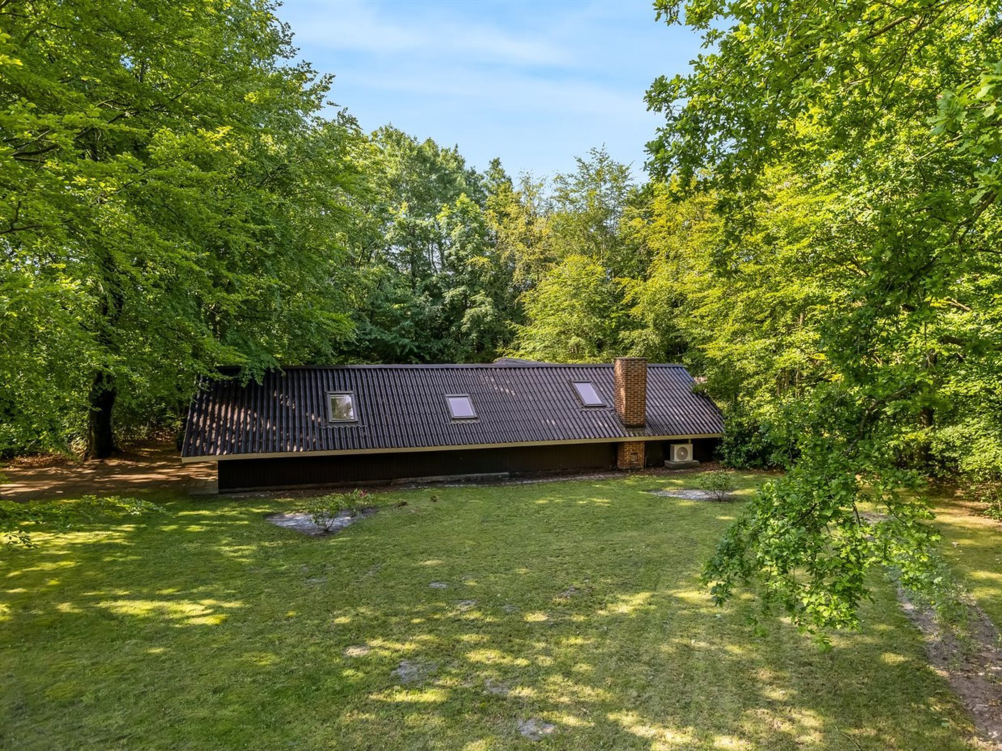 Ein Haus mit geneigtem Dach, umgeben von üppigem Grün.