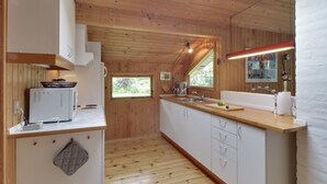 A compact kitchen with wooden walls, a skylight, and a large window.
