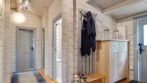 Een vakantiehuisje van binnen, met een houten bank, kapstok en kastjes.