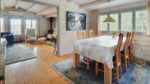 Een ruime woonkamer met een grote houten eettafel, een open haard en een schilderij aan de muur.