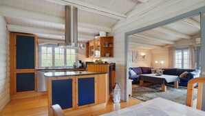 Een ruime woonkamer met een keuken, houten vloeren en een groot raam.