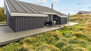 Una casa moderna con techo inclinado, una terraza y un pequeño espacio de asientos al aire libre.