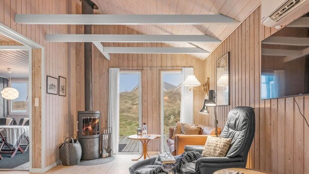 Un cuarto acogedor con chimenea, un sillón de cuero, pisos de madera y vistas al exterior.