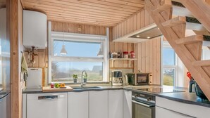 Una cocina moderna con detalles de madera, lavavajillas integrado, microondas y cafetera.