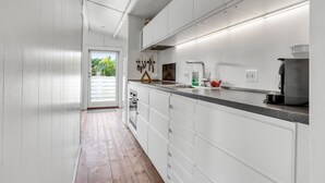 A modern kitchen with white cabinetry, a wooden floor, and a view of greenery outside. - "Heinke" - 2km from the sea by Interhome (Fanø)