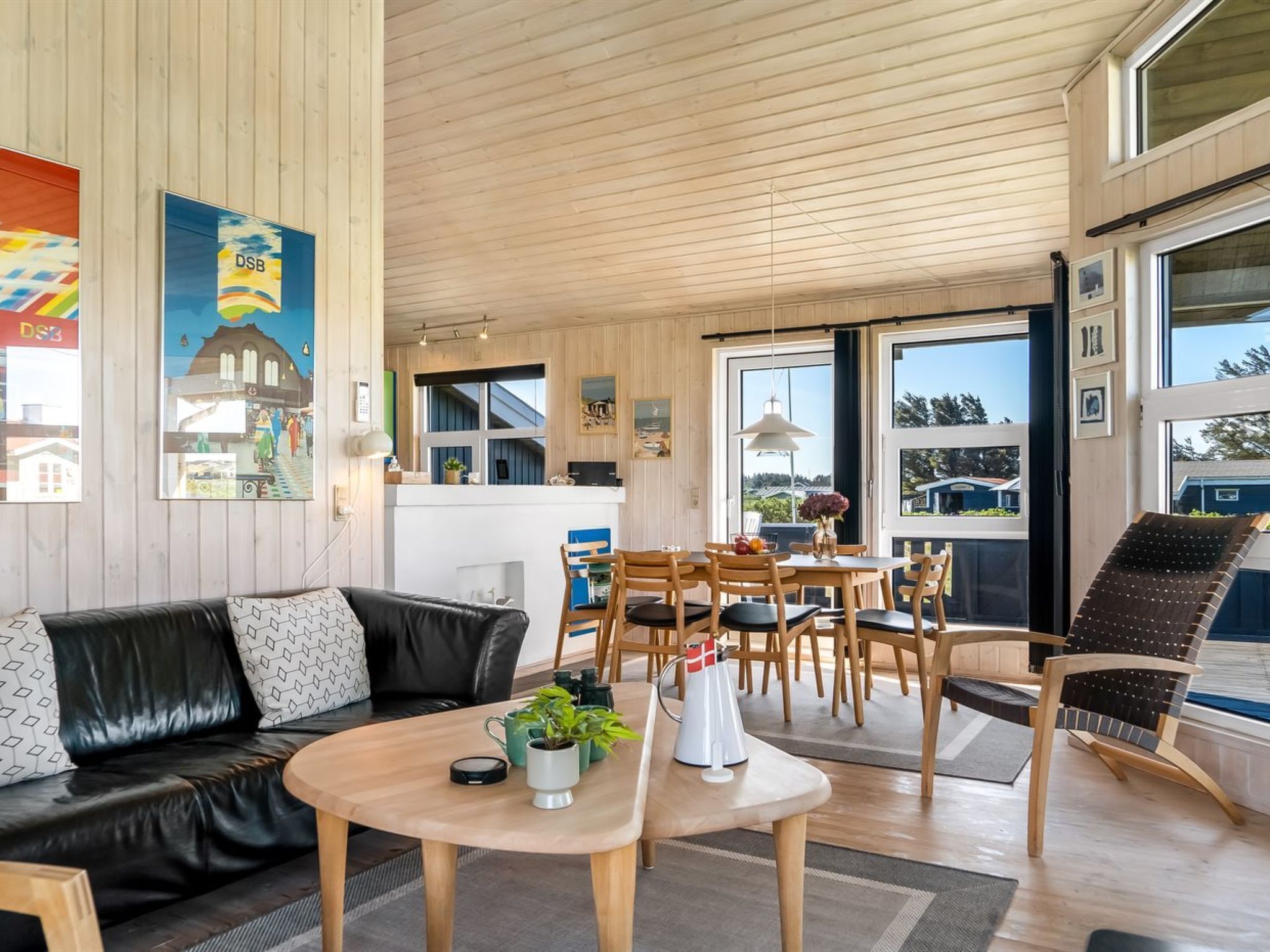 Un salon chaleureux avec un canapé en cuir, une table à manger et des chaises, ainsi qu’une grande fenêtre donnant sur l’extérieur.