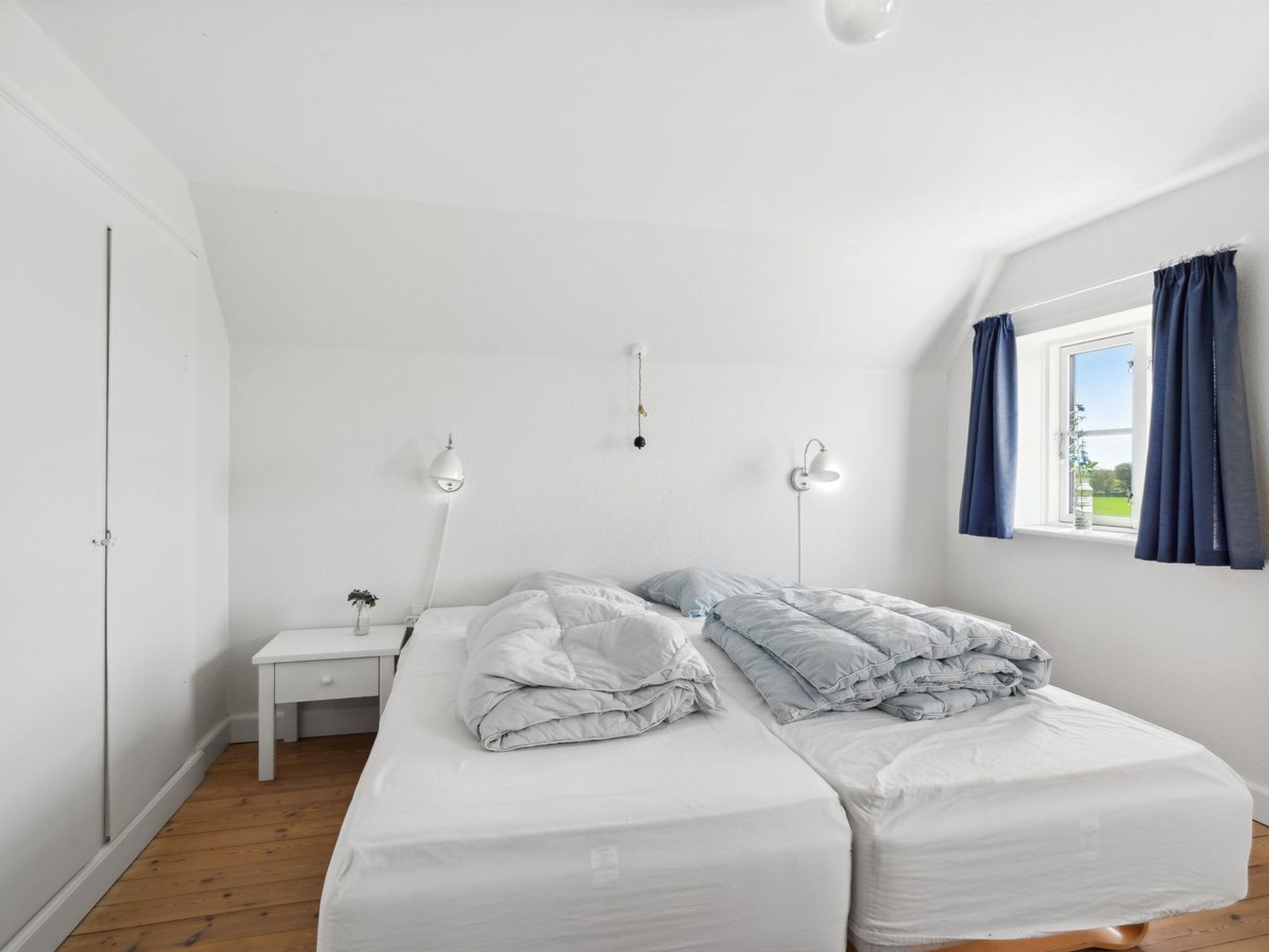 Een slaapkamer met een bed, nachtkastjes en een raam met gordijnen.