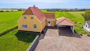 A large yellow house with a red roof, a garage, and a well-maintained lawn.