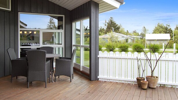 Eine Terrassengrundstück mit Essbereich, großen Fenstern und Blick auf die Nachbarschaft.