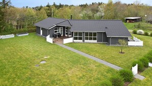 Ein modernes, zweistöckiges Haus mit einer großen Terrasse und einem überdachten Außenbereich.