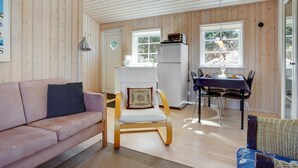 Un intérieur de chalet chaleureux, avec un revêtement en bois, un coin repas et un canapé.