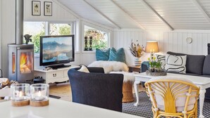 Ein gemütliches Wohnzimmer mit Kamin, Fernseher, bequemen Sitzmöglichkeiten und einem Essbereich mit Kerzen.