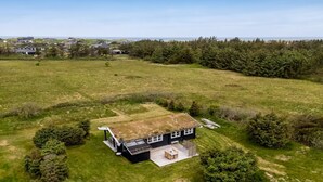 A house with a large lawn, a deck, and a view of the ocean.
