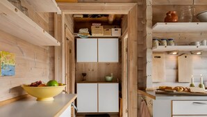 A narrow kitchen with wooden walls and cabinets, a yellow bowl with fruits on the counter, and a small sink.