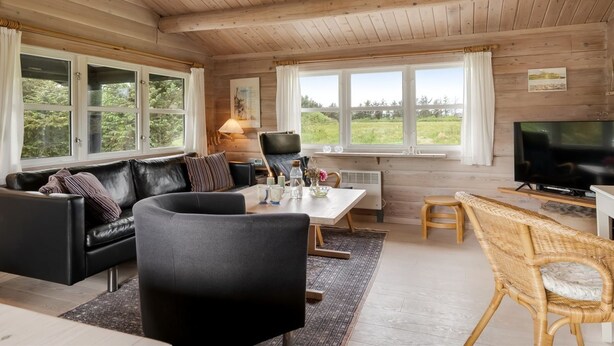 A cozy living room with a black leather sofa, a dining table, and a television.