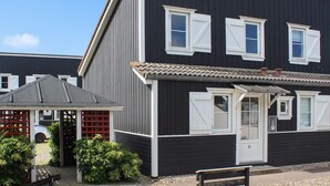 A two-story building with a dark facade and white trim. There is a small porch with a red lattice and a bench. - "Eleen" - 100m to the fjord by Interhome (Vestervig)