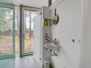 Bathroom with a glass door leading to the backyard, featuring a sink, mirror, and towel rack.