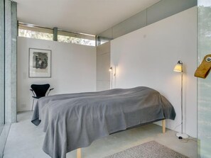 Relax in a serene bedroom with a large bed, a stylish chair, and a unique artwork.