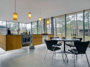 Enjoy cooking in this kitchen with a central island, oven, and dishwasher, surrounded by windows offering a view of the surrounding forest.