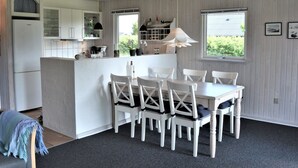A modern kitchen with white cabinetry, a central island with seating, and a dining area with white chairs. - "Kustaa" - 1km from the sea by Interhome (Humble)