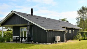 A black metal building with a sloped roof, a covered porch, and a small garden area. - "Kustaa" - 1km from the sea by Interhome (Humble)
