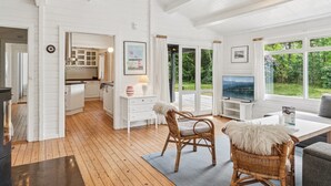 A spacious living area with a wooden floor, white walls, and large windows offering a view of the outdoors. - "Nititzki" - 600m from the sea by Interhome (Nykøbing Sj)