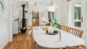 A spacious dining area with a white table and chairs, a hanging light fixture, and a view of the kitchen and living area. - "Nititzki" - 600m from the sea by Interhome (Nykøbing Sj)