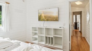 Ein Schlafzimmer mit einem Bett, einem an der Wand montierten Fernseher und Holzboden.