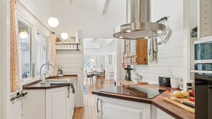 A kitchen with white cabinetry, wooden flooring, and a central island with a sink. - "Nititzki" - 600m from the sea by Interhome (Nykøbing Sj)