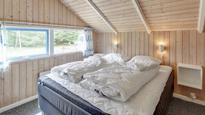 Een kamer met houten lambrisering, een bed, een raam en een wandlamp.