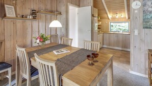Een houten eethoek met een tafel, stoelen en een vaas bloemen.