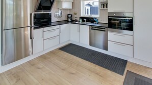 A modern kitchen with stainless steel appliances, white cabinetry, and a wooden floor. - "Aatos" - 500m from the sea by Interhome (Fanø)