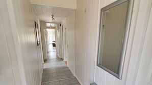 A narrow hallway with white paneling and a tiled floor, leading to a room with a large mirror and a door. - "Aatos" - 500m from the sea by Interhome (Fanø)
