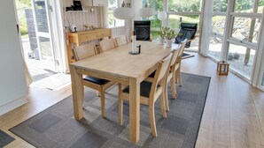 A spacious dining area with a wooden table and chairs, a kitchen with white cabinets, and large windows offering a view of the outdoors. - "Aatos" - 500m from the sea by Interhome (Fanø)