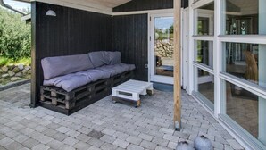A covered outdoor seating area with a wooden bench and a cushioned bench. - "Aatos" - 500m from the sea by Interhome (Fanø)