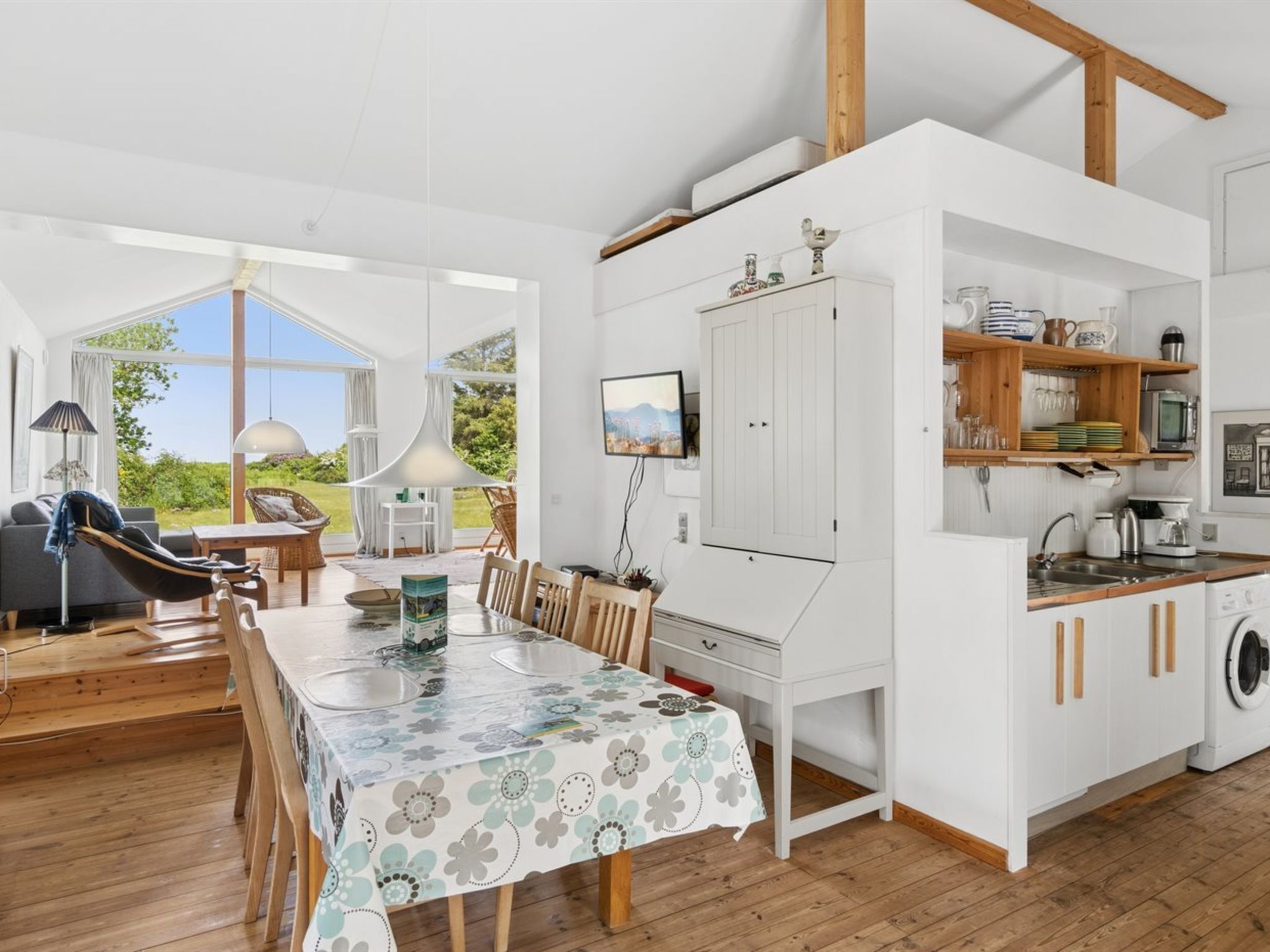 A spacious living area with a dining table, a sofa, and a view of the outdoors.