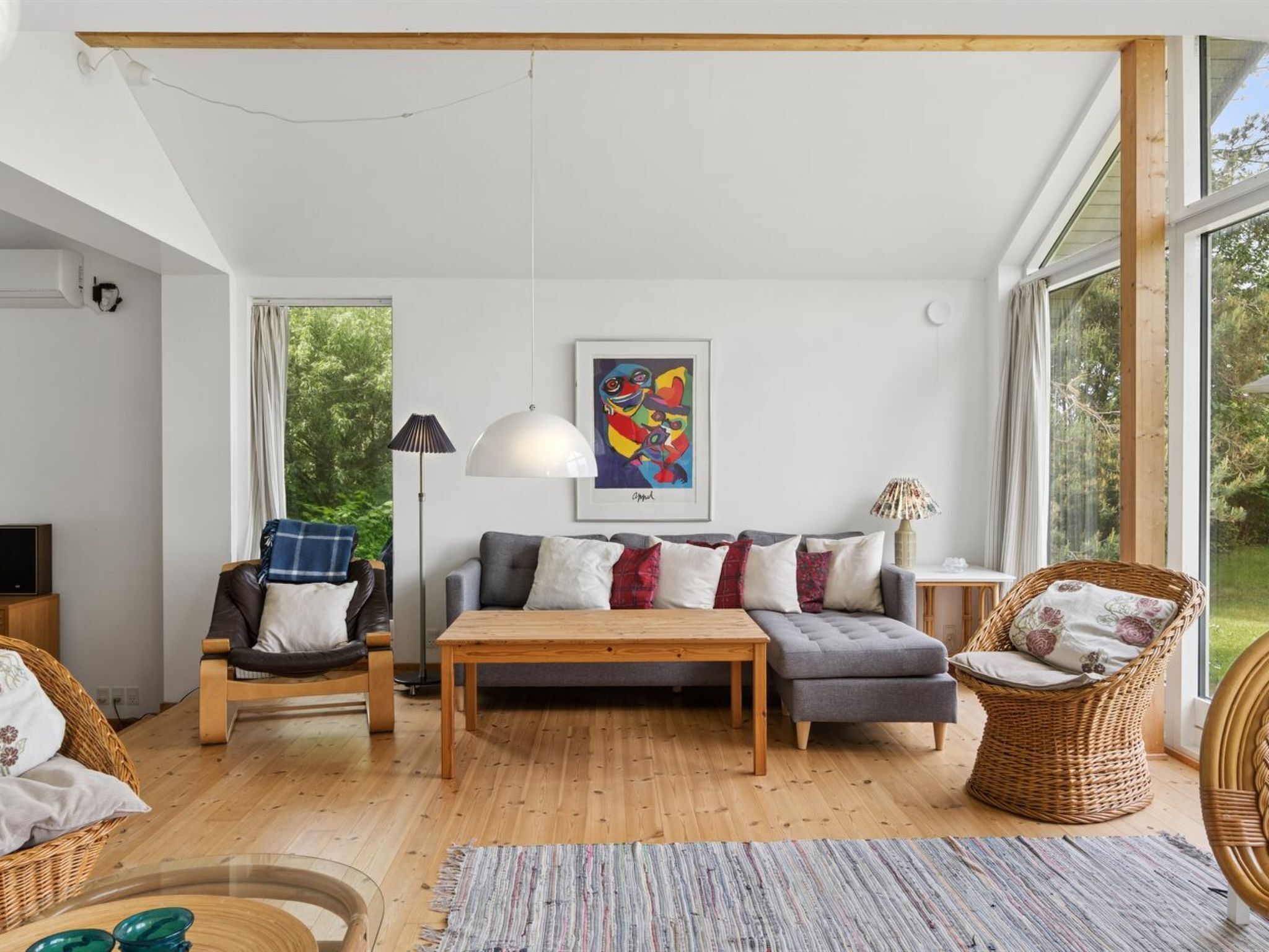 A modern living room with a sofa, coffee table, and wicker chairs.