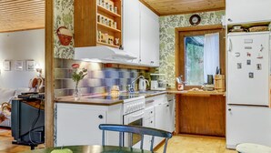 Uma cozinha compacta com armários brancos, bancada de madeira e uma janela.