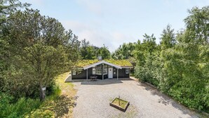 Une maison moderne avec un toit en pente, une allée en gravier et un petit jardin.